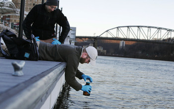 Researchers next to a river collecting water samples